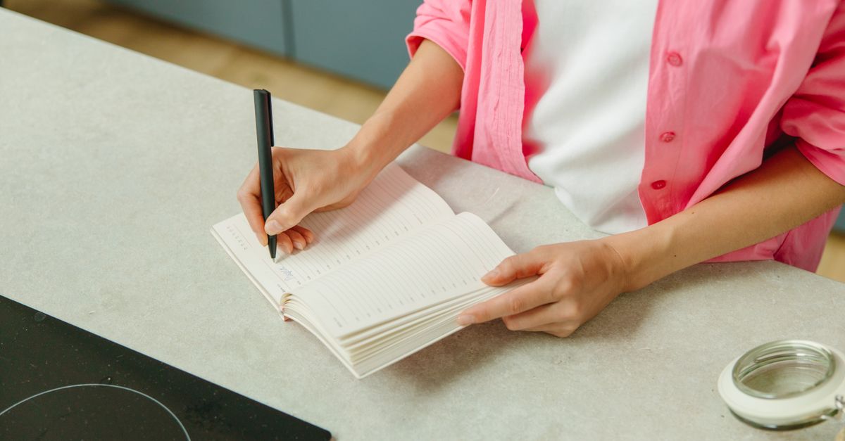 A bright kitchen counter with a tablet showing a family shopping list next to a reusable grocery bag.